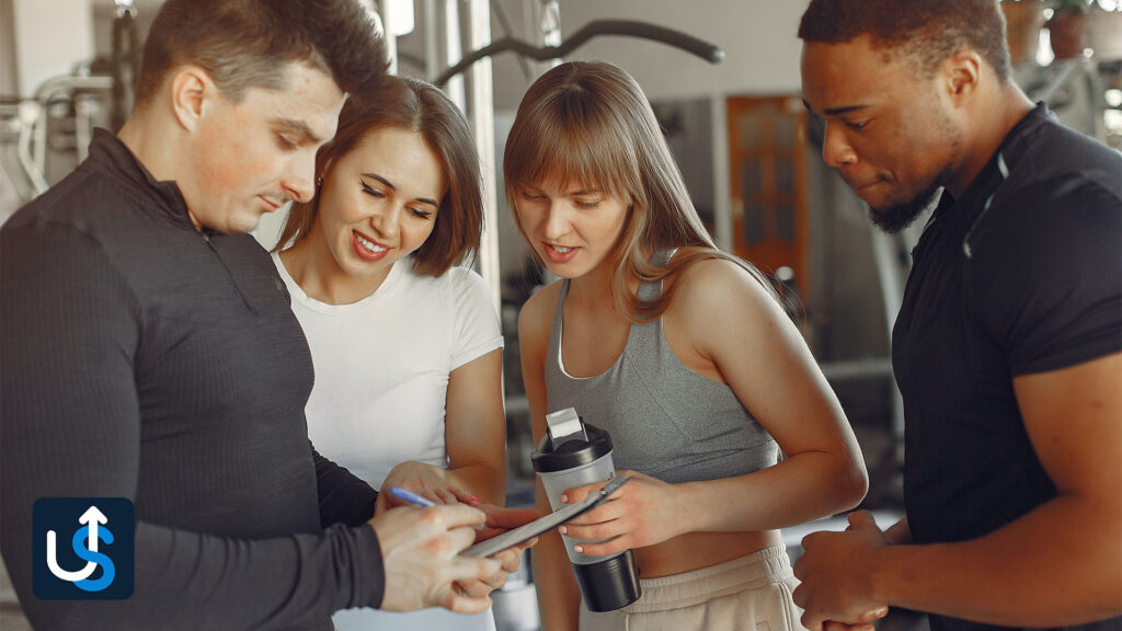 A group of people looking at a tablet in a gym.