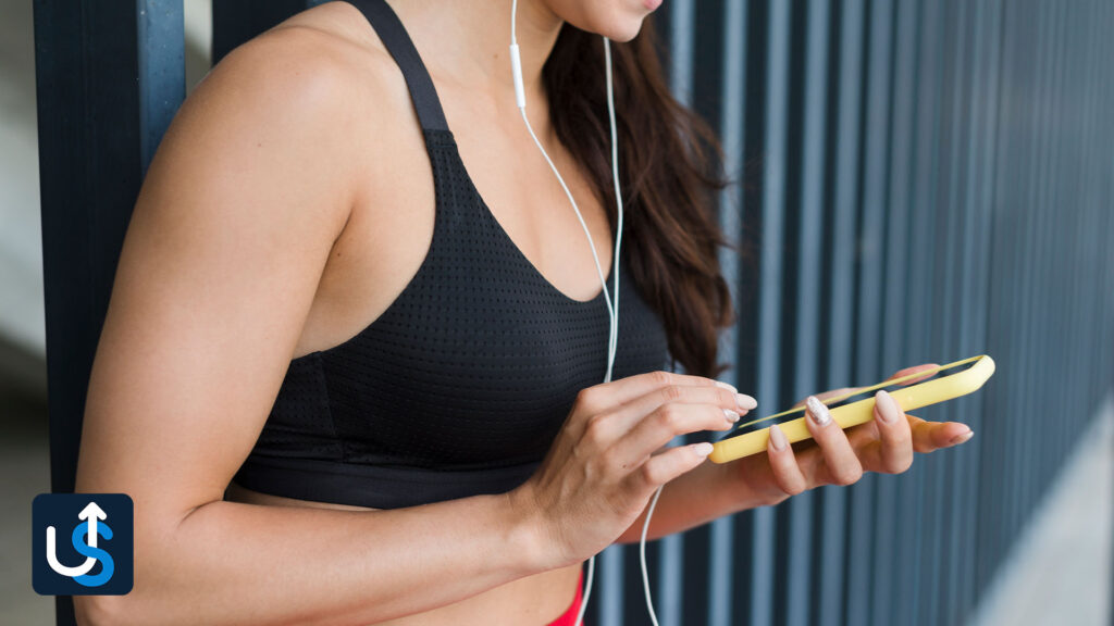 A woman holding a cell phone while listening to music.