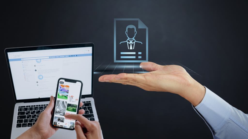 A hand holding a virtual profile icon, with a laptop displaying a document and a smartphone showing images, emphasizing digital connectivity and information sharing.