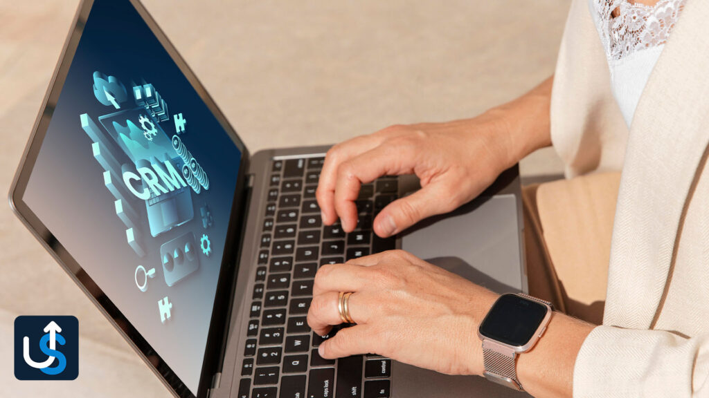 Person using a laptop with CRM (Customer Relationship Management) software on the screen, wearing a smartwatch.