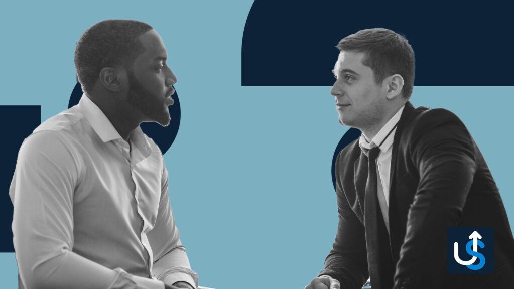 Two men in discussion against a blue background, with a business icon in the corner. One man wears a light shirt; the other wears a suit.