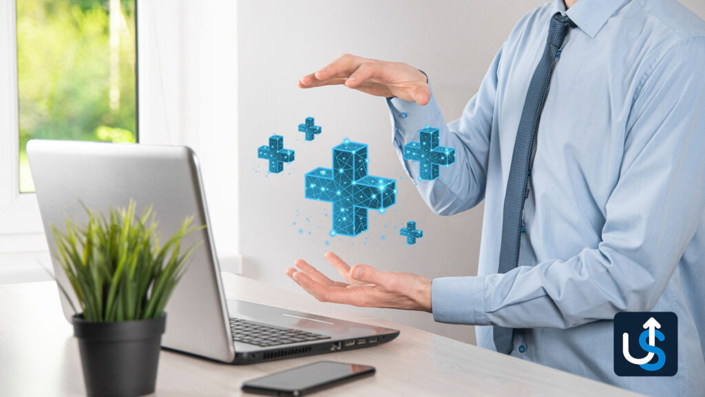 A person in a suit uses their hands near a laptop to display floating holographic plus signs, symbolizing a futuristic or tech-related concept. A potted plant is on the desk.