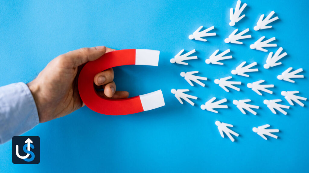 A hand holds a red horseshoe magnet attracting white human figures on a blue background, suggesting the concept of attracting people or customers.