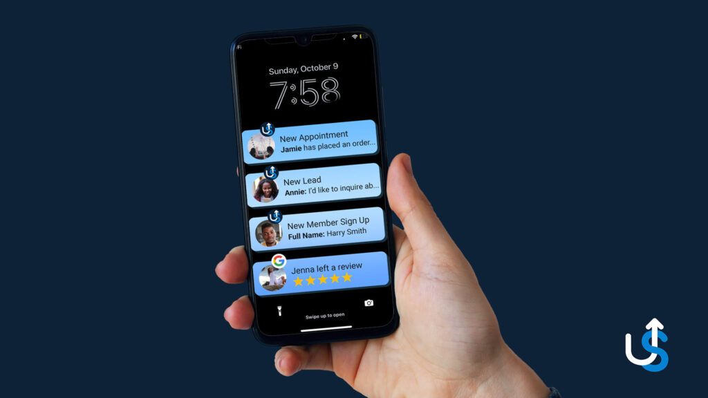 A hand is holding a smartphone displaying various notifications, including a new appointment, new lead, new member sign-up, and a review. The screen shows the time as 7:58 on Sunday, October 9.