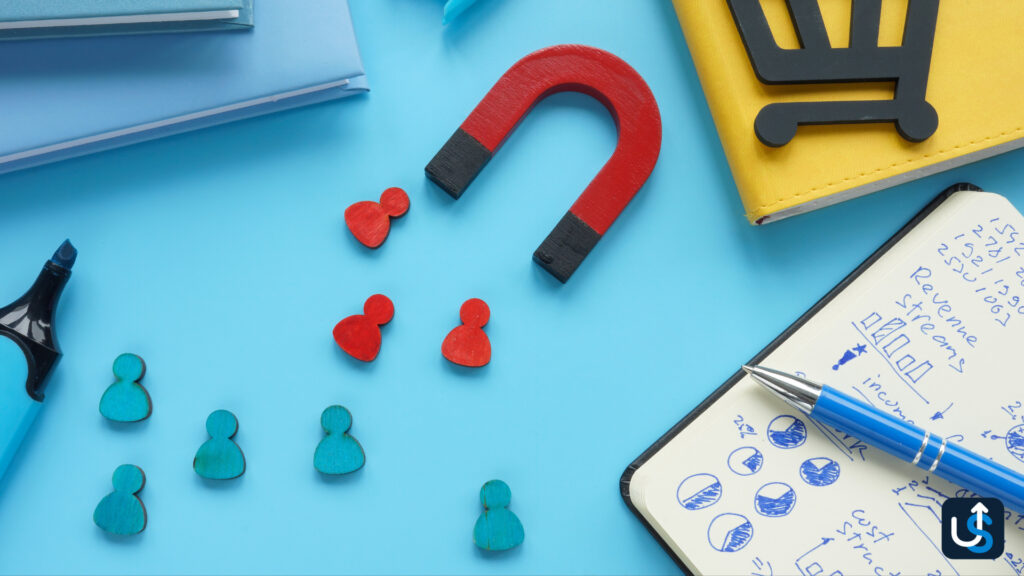 A magnet attracting red people icons, while blue ones remain, hints at how accounting firms draw clients. Nearby are a notebook with charts, a pen, a highlighter, and a shopping cart symbol on a yellow wallet.