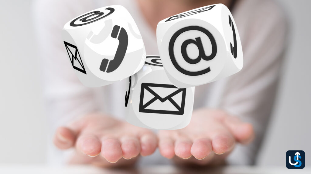 Floating cubes with communication symbols: email, phone, and mail, above a person's open hands.